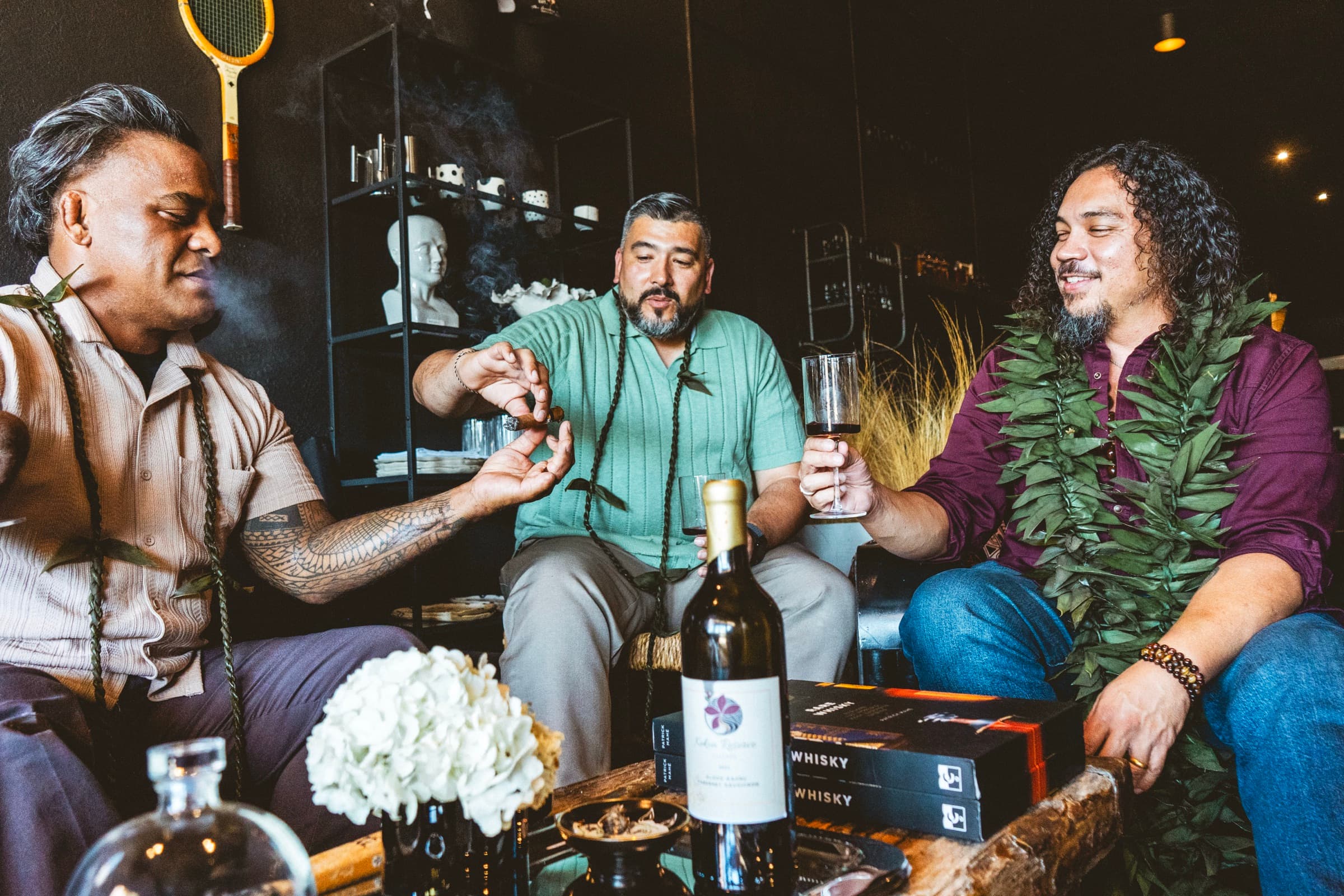 Koa Kekoa laughing with friends over glasses of wine