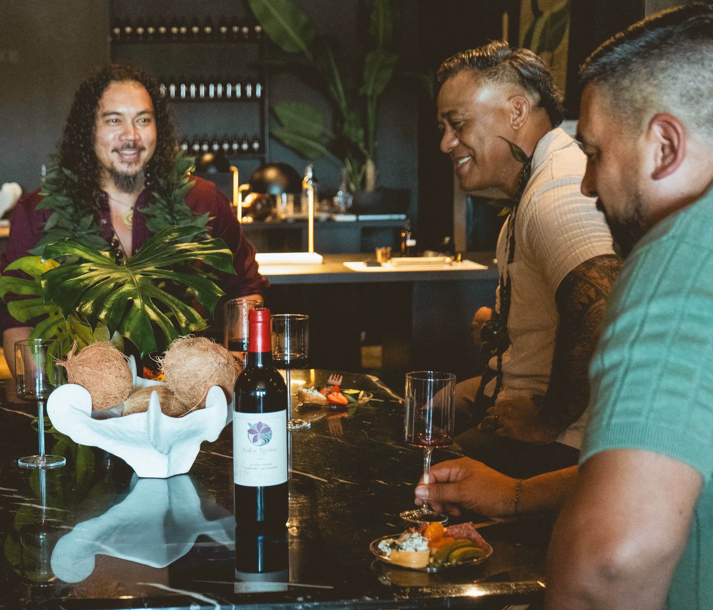 Friends around a table with a bottle of Kekoa Reserve, mid-laugh